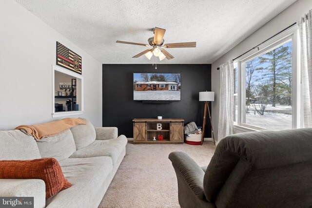 carpeted living area featuring a textured ceiling, ceiling fan, and baseboards