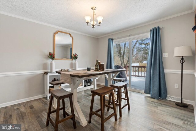 dining space with a chandelier, a textured ceiling, wood finished floors, and baseboards