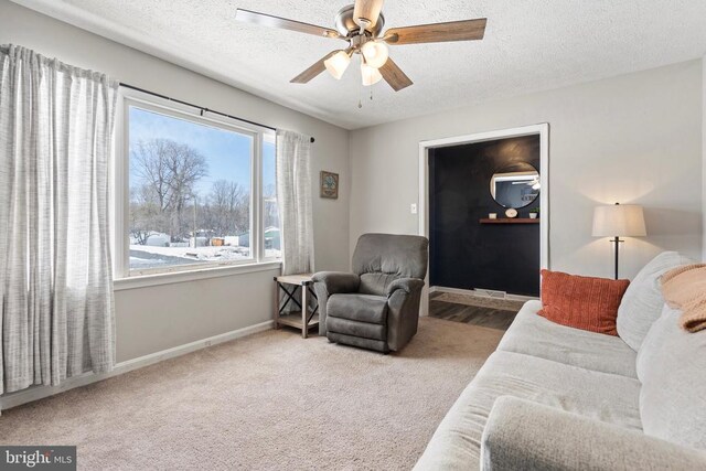 living room with carpet flooring, ceiling fan, a textured ceiling, and baseboards