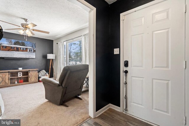 entryway with ceiling fan, a textured ceiling, baseboards, and wood finished floors