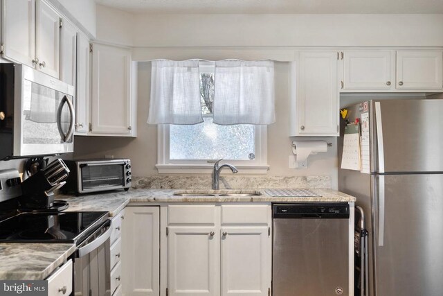 kitchen with appliances with stainless steel finishes, a sink, and white cabinets