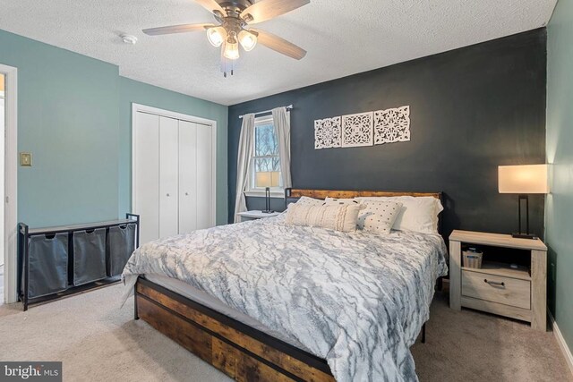 bedroom with carpet floors, a textured ceiling, a ceiling fan, and a closet