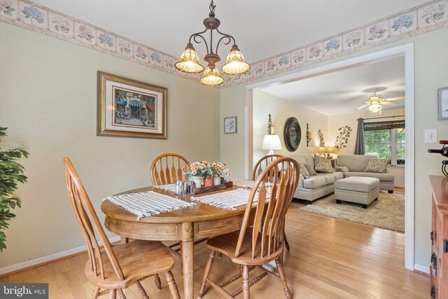 dining area with ceiling fan with notable chandelier and light hardwood / wood-style flooring