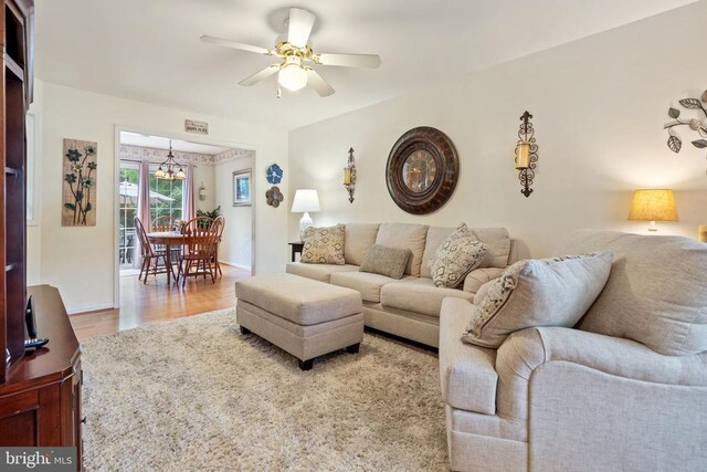 living room featuring ceiling fan with notable chandelier and hardwood / wood-style floors