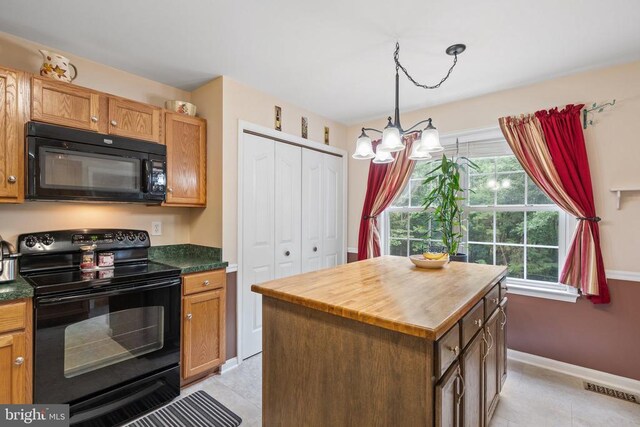 kitchen featuring butcher block countertops, light tile patterned floors, black appliances, a kitchen island, and decorative light fixtures