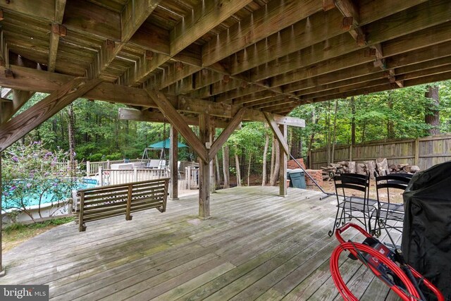 wooden terrace with a fenced in pool, grilling area, and outdoor lounge area