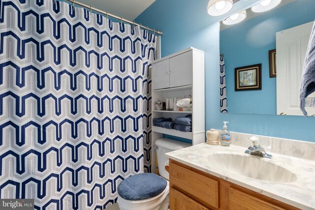 bathroom with walk in shower, vanity, and toilet