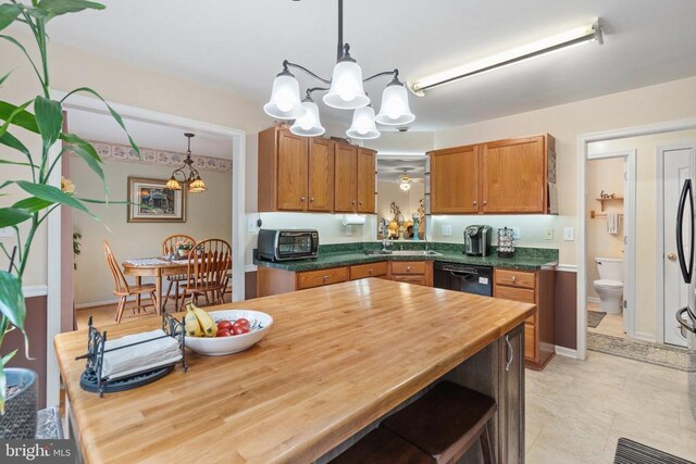 kitchen featuring ceiling fan with notable chandelier, decorative light fixtures, sink, black dishwasher, and wooden counters