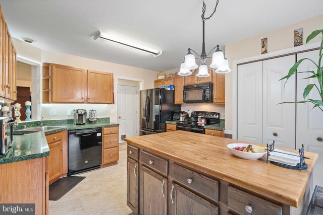 kitchen with sink, butcher block counters, hanging light fixtures, black appliances, and a kitchen island