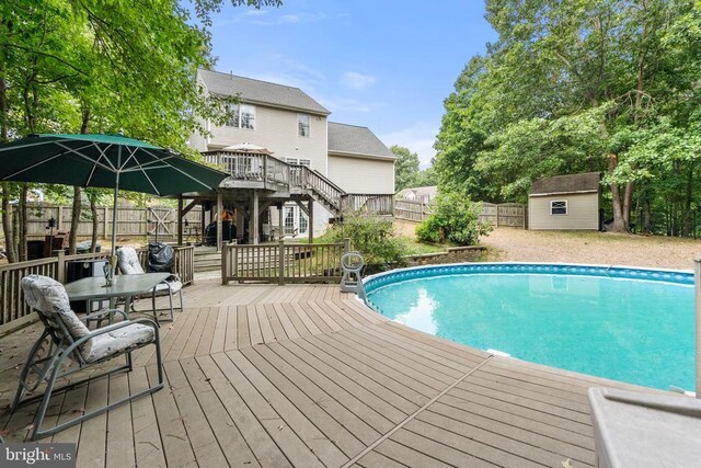 view of swimming pool featuring a wooden deck and a shed