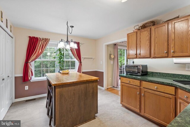 kitchen with wood counters, decorative light fixtures, a center island, and a wealth of natural light