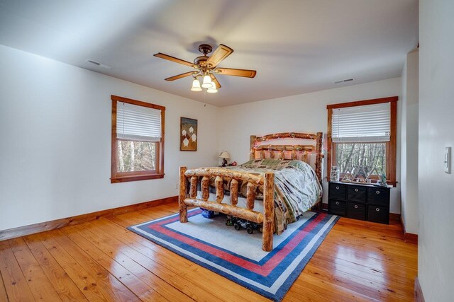 bedroom with multiple windows, wood-type flooring, and ceiling fan