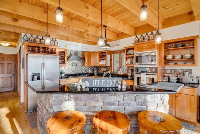 kitchen with stainless steel appliances, pendant lighting, wall chimney range hood, and a kitchen bar