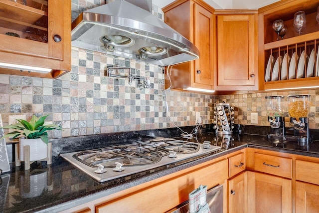 kitchen featuring backsplash, range hood, dark stone counters, and stainless steel gas stovetop