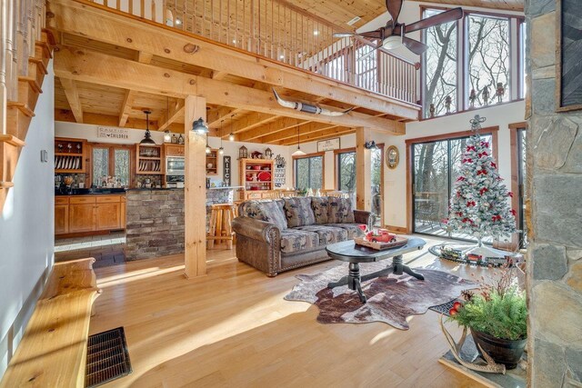 living room with ceiling fan, light hardwood / wood-style flooring, a healthy amount of sunlight, and indoor bar