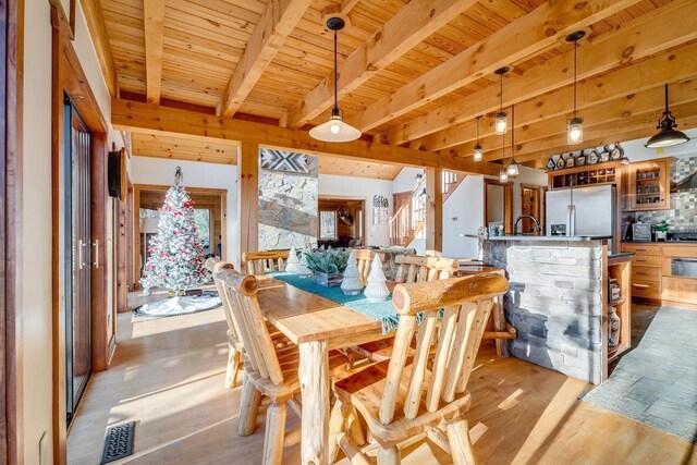 dining area featuring bar area, wooden ceiling, beam ceiling, and light hardwood / wood-style floors