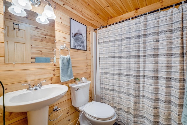 bathroom featuring curtained shower, wood walls, sink, wood ceiling, and toilet