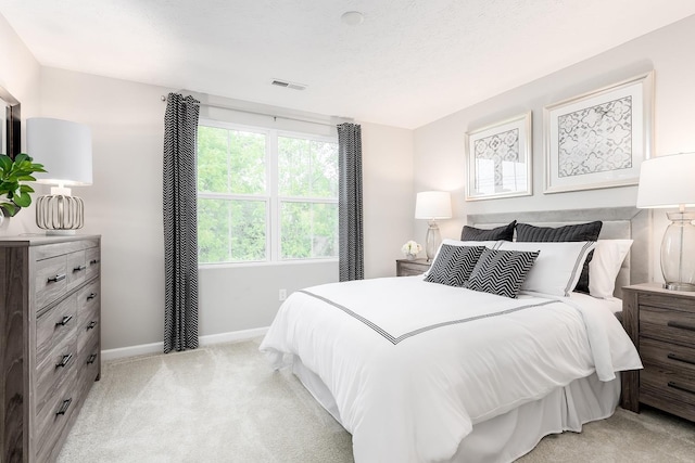 bedroom with baseboards, visible vents, and light colored carpet