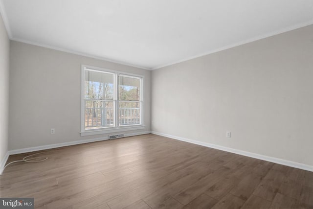 empty room featuring visible vents, baseboards, wood finished floors, and crown molding