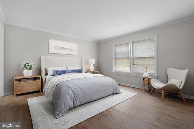 bedroom featuring crown molding, wood finished floors, and baseboards