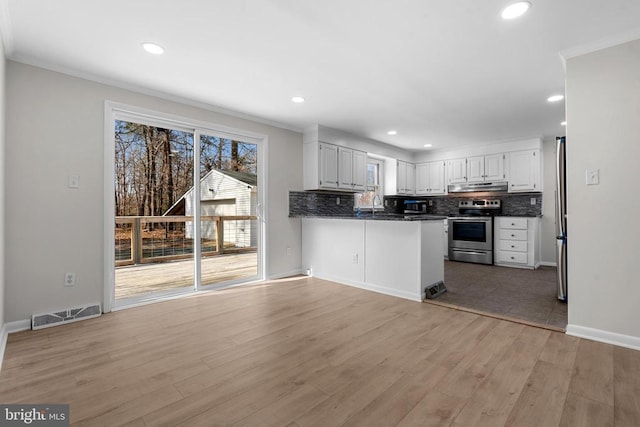 kitchen with visible vents, light wood-type flooring, under cabinet range hood, appliances with stainless steel finishes, and tasteful backsplash