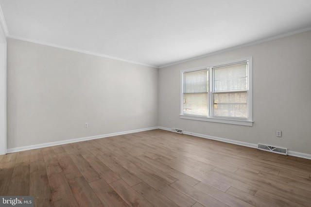 unfurnished room with crown molding, wood finished floors, and visible vents