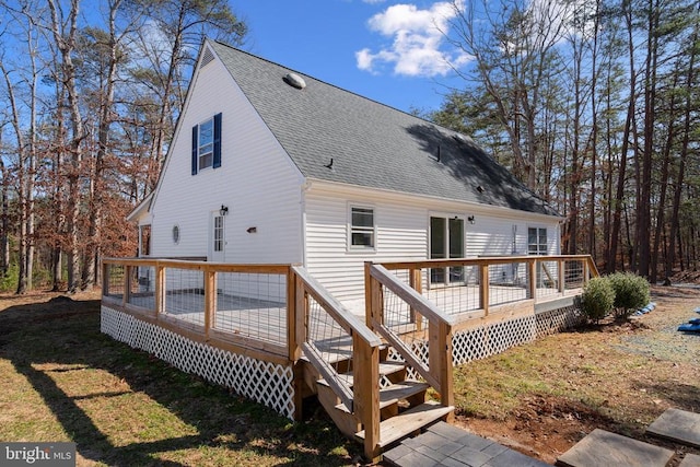 back of property featuring a deck, a yard, and roof with shingles