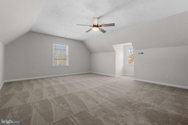 additional living space with visible vents, baseboards, a textured ceiling, and carpet flooring