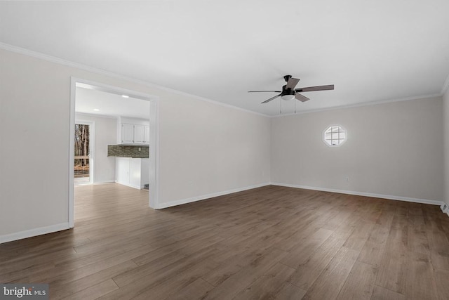 spare room featuring ornamental molding, baseboards, a ceiling fan, and wood finished floors