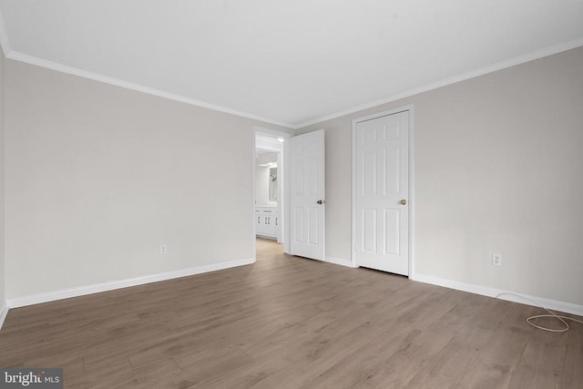 unfurnished bedroom featuring crown molding, wood finished floors, and baseboards