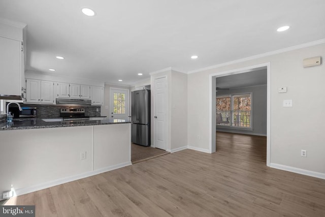 kitchen with a sink, under cabinet range hood, white cabinetry, stainless steel appliances, and a peninsula