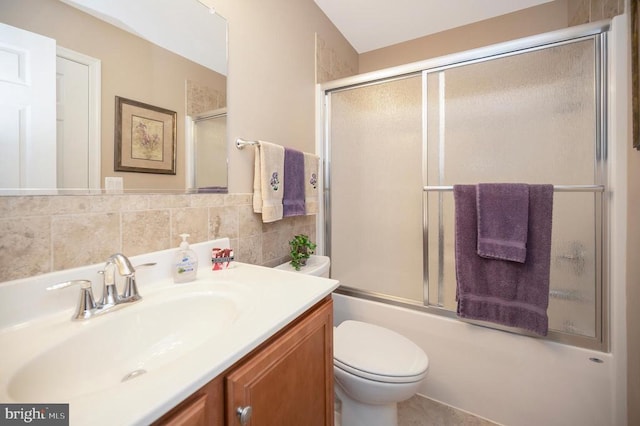 full bathroom with vanity, tile walls, toilet, and bath / shower combo with glass door