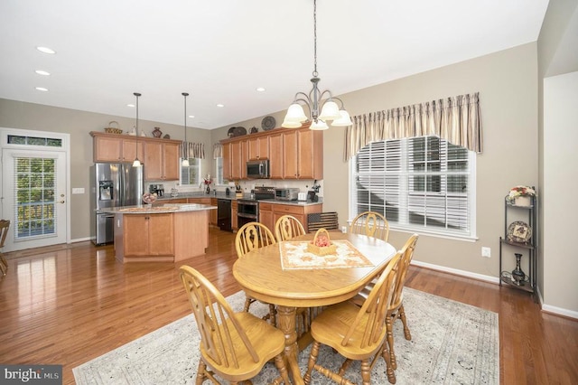 dining room with recessed lighting, light wood-type flooring, baseboards, and a notable chandelier