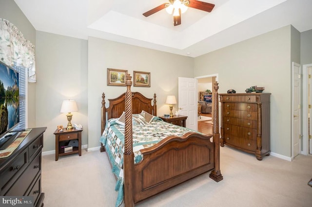 bedroom with light carpet, a raised ceiling, and baseboards