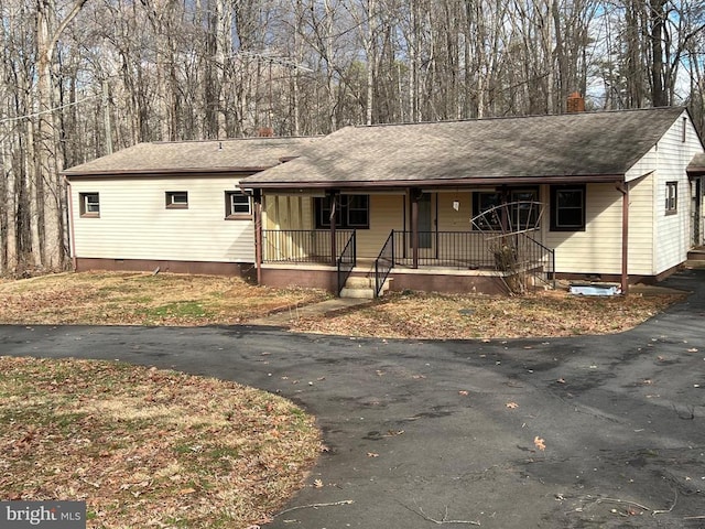 ranch-style home featuring crawl space, a shingled roof, and a porch