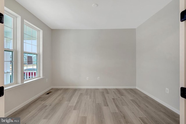 spare room featuring light wood-style floors, visible vents, and baseboards