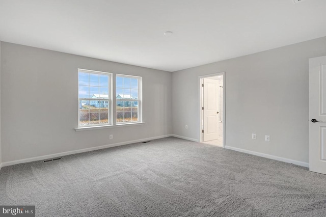 spare room with visible vents, baseboards, and light colored carpet