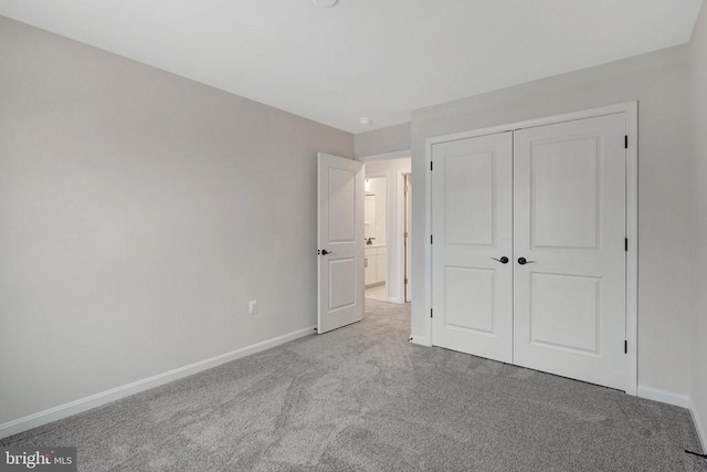 unfurnished bedroom featuring baseboards, a closet, and light colored carpet