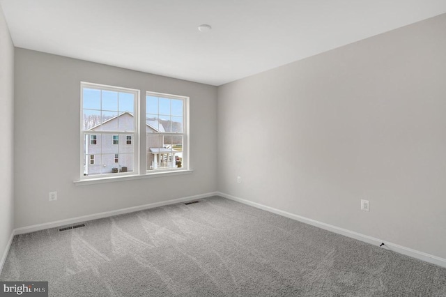 carpeted spare room featuring visible vents and baseboards