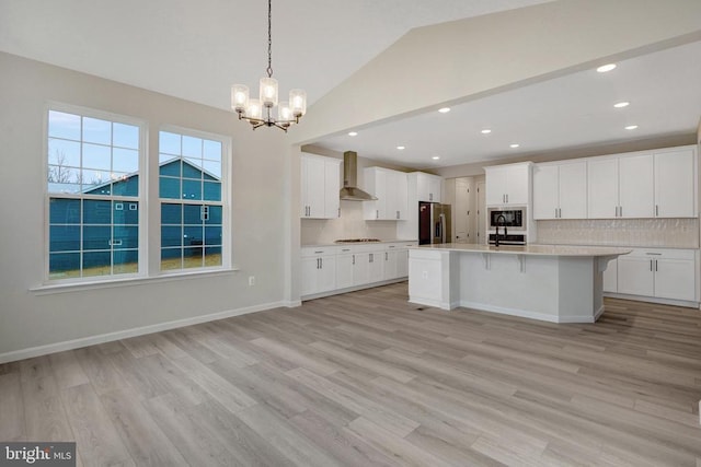 kitchen featuring stainless steel fridge, wall chimney exhaust hood, a kitchen island, light countertops, and black microwave