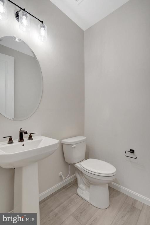 half bath with wood finished floors, toilet, and baseboards