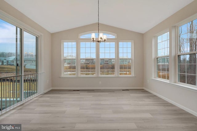 unfurnished dining area with vaulted ceiling, light wood-style flooring, baseboards, and an inviting chandelier