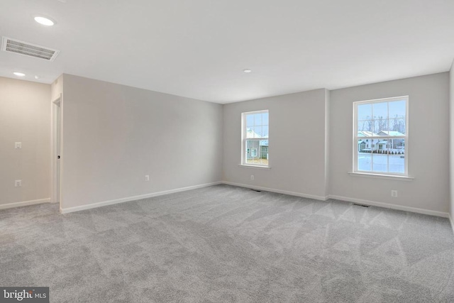 empty room featuring baseboards, visible vents, and light colored carpet