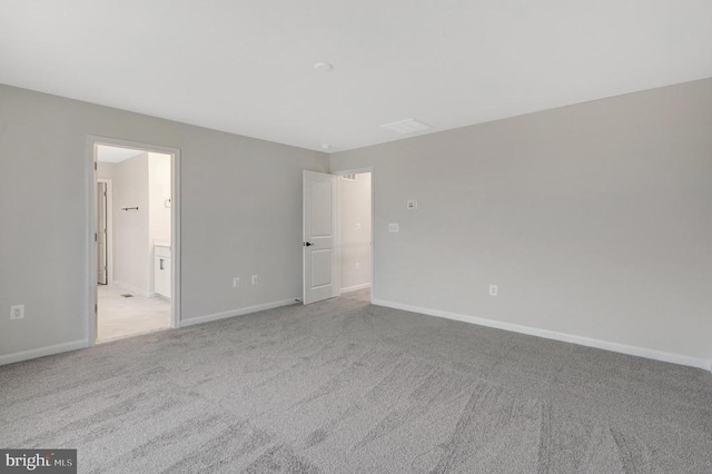 unfurnished bedroom featuring light carpet, ensuite bath, and baseboards