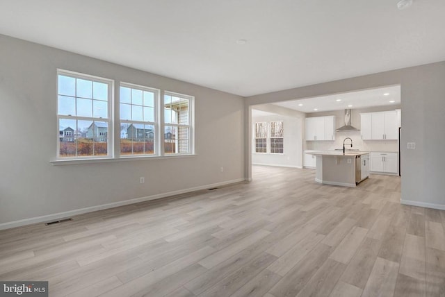 unfurnished living room featuring recessed lighting, a sink, visible vents, baseboards, and light wood-type flooring