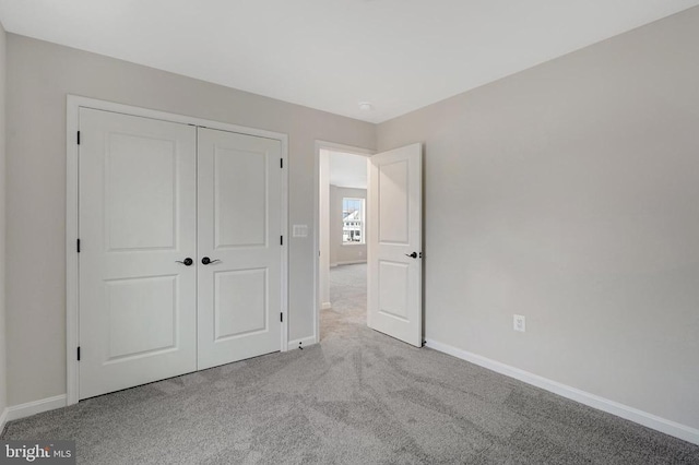 unfurnished bedroom featuring baseboards, a closet, and light colored carpet