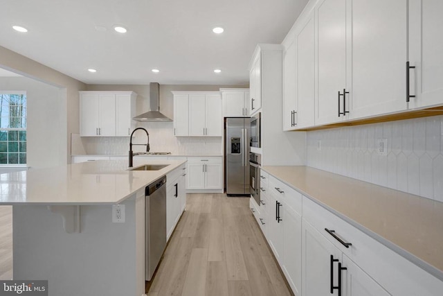 kitchen featuring white cabinets, wall chimney exhaust hood, light countertops, and a sink