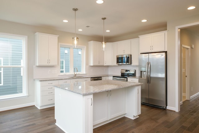 kitchen featuring sink, white cabinetry, appliances with stainless steel finishes, a kitchen island, and pendant lighting