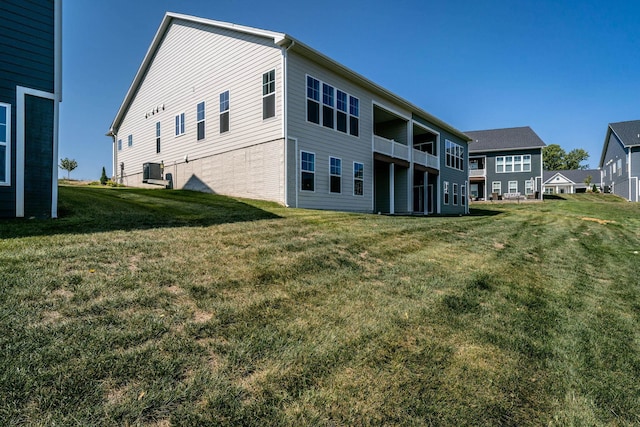 rear view of property with central AC unit and a yard