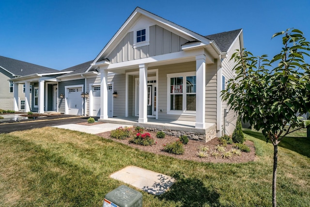 view of front of house with a garage, a porch, and a front lawn